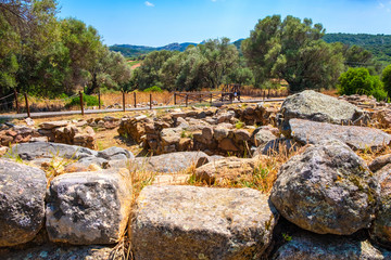 Fototapeta na wymiar Arzachena, Sardinia, Italy - Archeological ruins of Nuragic complex La Prisgiona - Nuraghe La Prisgiona - with remaining of rounded stone houses of Neolithic village