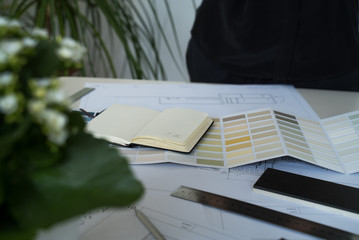 The interior designer selects wall paint samples. Designer at work. Architect desk. Decoration. Design project blueprints. Plans and drawings. Grey stone. Paint catalog. Decorative material. Flatlay