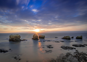 Fototapeta na wymiar Long exposure shot for a sunset over the rocks