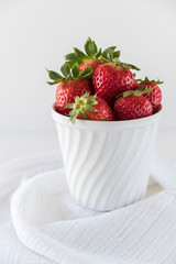Strawberries in a white porcelain bowl on white background