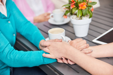 Fototapeta na wymiar Pflegekraft hält Hand einer Seniorin zum Trost