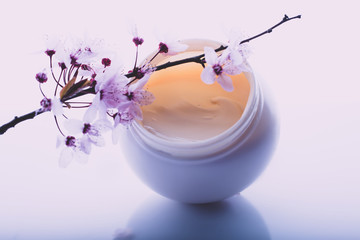 body cream and flowers on a light background