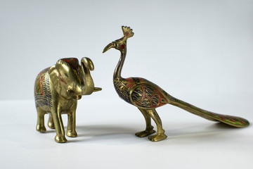 Obraz premium Small Golden Statues of Elephant and Peacock on White Background