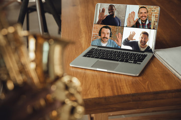 African-american musician playing saxophone during online concert at home isolated and quarantined....