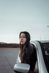 A young woman leaning over the window of a gray car