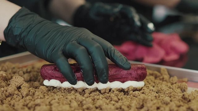 Eclairs or profiterole with chocolate and whipped cream preparing on baking sheet. Spreading chocolate on top of eclair with spoon. Traditional French dessert. 