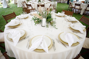 banquet table is decorated with plates, cutlery, glasses, candles and flower arrangements