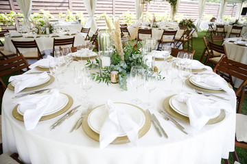 banquet table is decorated with plates, cutlery, glasses, candles and flower arrangements