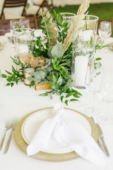 banquet table is decorated with plates, cutlery, glasses, candles and flower arrangements
