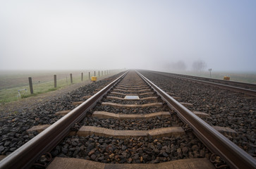 Fototapeta premium Empty railroadtracks disapearing into the spring fog.