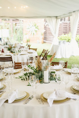 banquet table is decorated with plates, cutlery, glasses, candles and flower arrangements