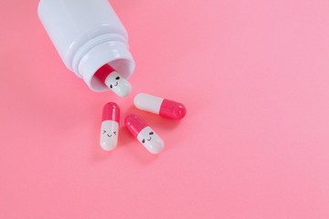 Pink white pills fall out of the bottle close up on pink background. Choose your mood