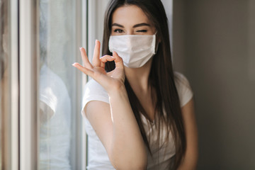 Young woman take off protective mask. Female in white t-shirt and white medical mask. End of quarantine. Coronavirus theme