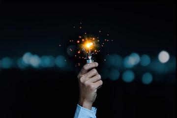 Businessman holding lightbulb which it glowing on black background and copy space .Creativity idea...