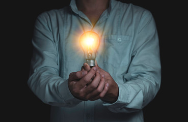 Businessman holding lightbulb which it glowing on black background and copy space .Creativity idea concept.