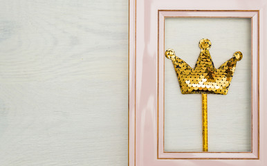 Pink photofrme with golden sequins crown on white wooden backgound. Minimal flat lay with copy space
