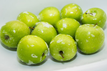 Obraz premium .Washing fruit. Soapy green apples in the sink. Washing fruits and vegetables for the prevention of coronavirus covid-19 2019-ncov