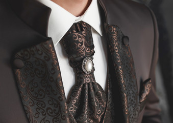 Luxurious modern expensive brown wedding men's suit with an abstract pattern and pearls on a tie...