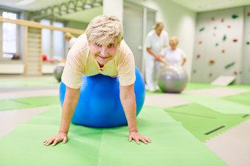 Senior woman doing back exercise on gym ball