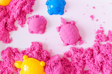 Pink magic sand shaped turtle and fish on a white background. Early sensory education. Preparing...