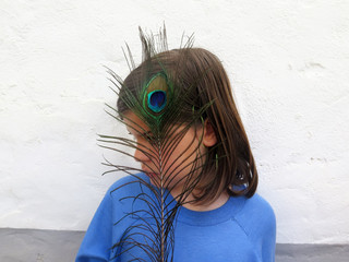 Girl with peacock feather covering her face