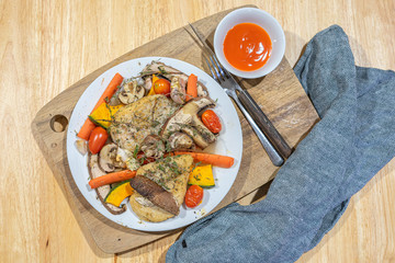 Baked and grilled chicken steak with mushroom, pumpkin and carrot on wooden table.