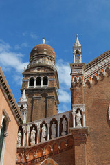 Fototapeta na wymiar Detail of the facade and bell tower of the church of the Madonna dell'Orto in Venice. The building is in Venetian Gothic style, made of brick with decorative elements in stone and marble. Italy.