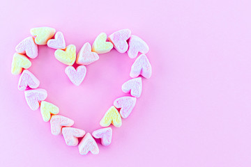 Heart shape made of bright marshmallows on a pink background. Abstract concept of love, Valentine's Day, confession of feelings. Copy space.