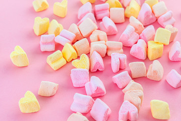 Colorful, light pink, yellow and peach love hearts on a pink background. Valentine's day wallpaper, festive background. Soft focus.