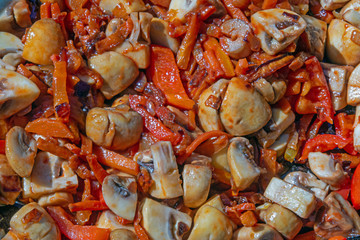 Sliced champignon mushrooms with red paprika, carrots and onions are fried in a saucepan. Cooking healthy and wholesome vegetarian food, keto, lchf. Cook at home.