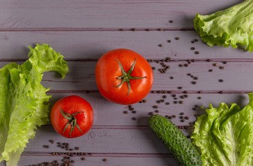 Fresh tomatoes, cucumbers, lettuce and peppers are on the table.