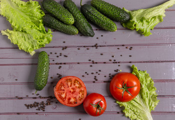 Fresh tomatoes, cucumbers, lettuce and peppers are on the table.