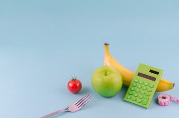 Diet, healthy eating, food and weight loss concept - close up of green apple, measuring tape and calculator