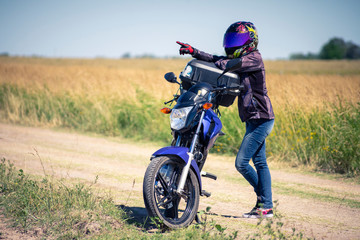 Obraz na płótnie Canvas Mujer motociclista sola en el campo con su motocicleta