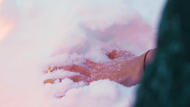 CU, slow motion: mature woman hand with manicure and red thread dipped in white snow near burning bonfire in winter extreme closeup