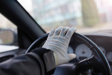 driver's hands in medical gloves on the steering wheel, driver safety in a pandemic.