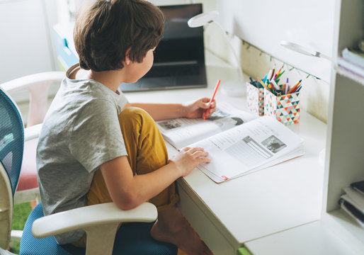 Tween Boy Do Homework Learn Foreign Language Writing In Pupil Book With Opened Laptop At Room Home Dictance Education