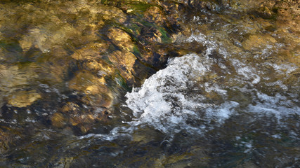 Kleine Welle im Bach, sprudelndes Wasser über Steinstufe