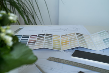 The interior designer selects wall paint samples. Designer at work. Architect desk. Decoration. Design project blueprints. Plans and drawings. Grey stone. Paint catalog. Decorative material. Flatlay