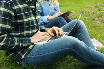 Man with laptop and woman with tablet work in park. Outdoor work