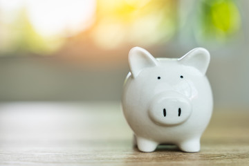 Money savings concepts Piggy bank symbol of saving money on wooden table with sunlight bokeh blur...