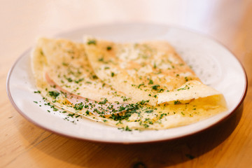 A ham and cheese crêpe on a plate at a restaurant