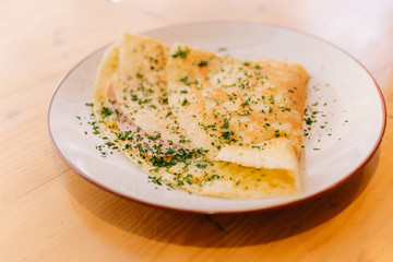 A ham and cheese crêpe on a plate at a restaurant
