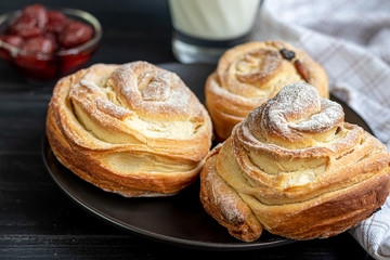 Bakery products with raisins and dried fruits are located on a dark wooden background. Sprinkled with icing sugar. Kraffins. Easter food.