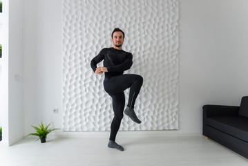 Instructions for calisthenics. Home fitness. COVID-19 concept. Exercises for all muscle groups. Muscular man demonstrates gymnastic exercises. Squatting with a knee-raising is the end.