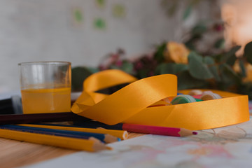 Watercolor paint, color pencils, brushes and white paper and flower on a wooden table. Hobby. Art. Childhood. Selective focus. Medium sharp