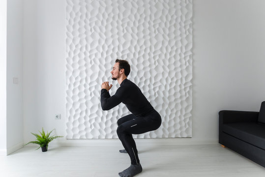 Instructions for calisthenics. Home fitness. COVID-19 concept. Exercises for all muscle groups. Muscular man demonstrates gymnastic exercises. Squat with raising legs and arms is the beginning.