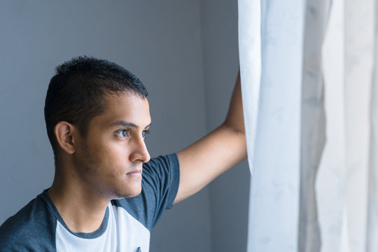 hombre latino retra&iacute;do mirando hacia la ventana, pensativo mirada perdida, miedo, temor