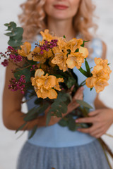 A beautiful floral bouquet is held by a young girl who is blurred.  She is wearing a blue dress. п9Selective focus. Medium sharp