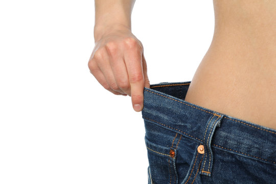 Girl pulling her big jeans and showing weight loss, isolated on white background